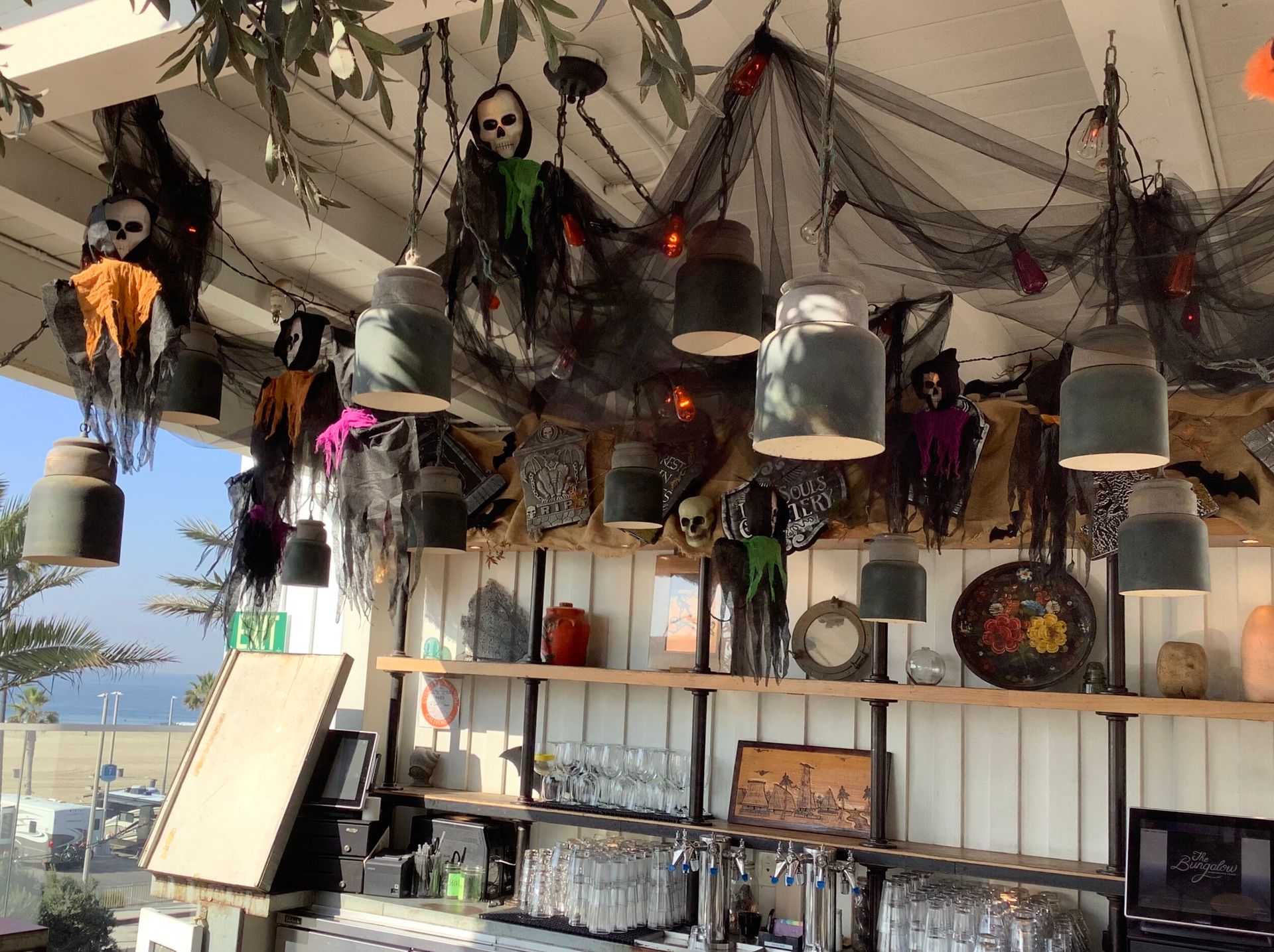 A beachfront patio bar decorated with hanging ghost figures and skulls